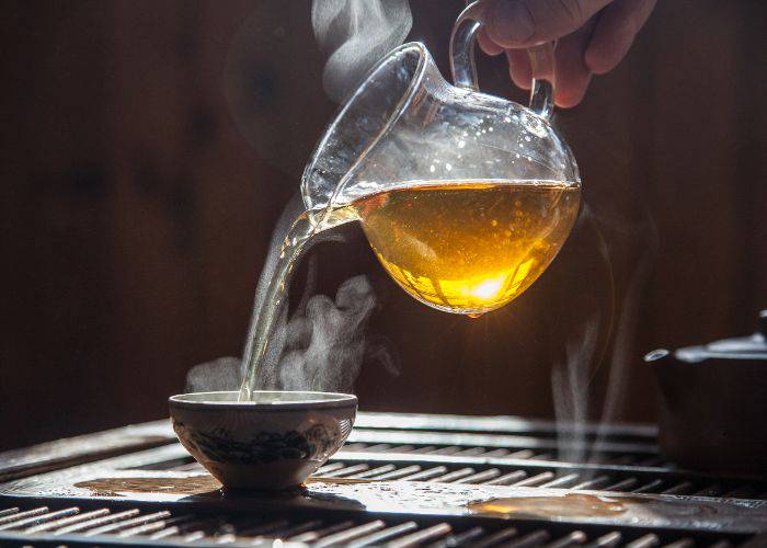 Japanese tea being poured into a small cup, with steam floating up.